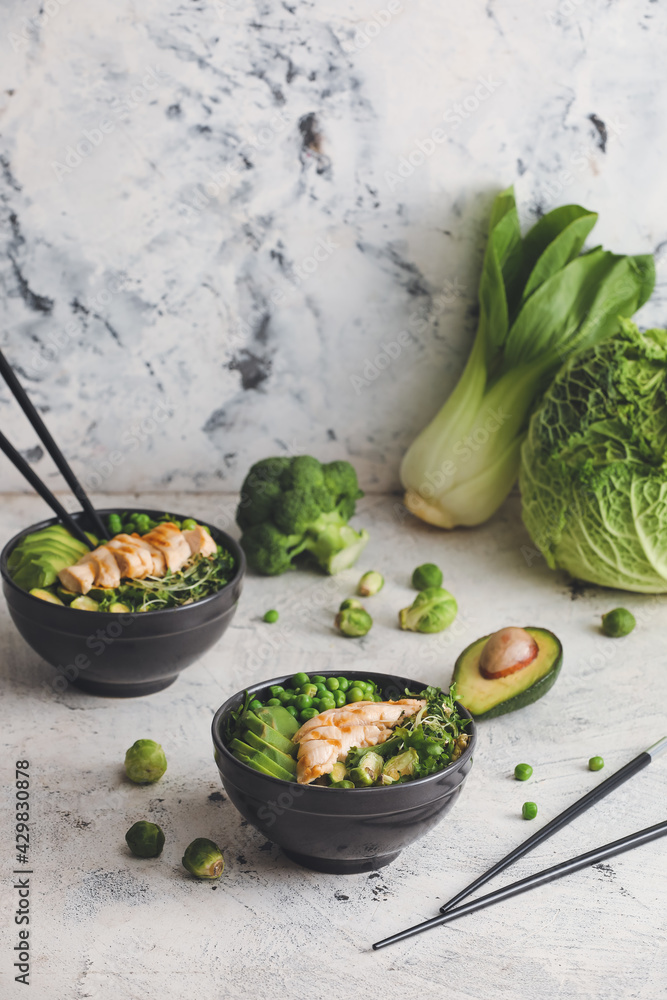 Wall mural Bowls of tasty salad with fresh vegetables and chicken on light background