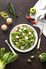 Plate of tasty salad with fresh vegetables on dark background