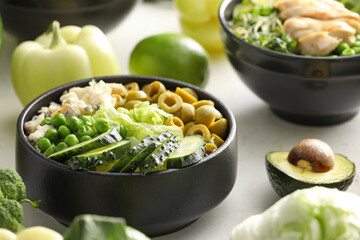 Bowls of tasty salad with fresh vegetables on light background