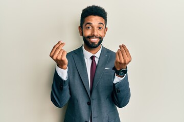 Handsome hispanic man with beard wearing business suit and tie doing money gesture with hands, asking for salary payment, millionaire business