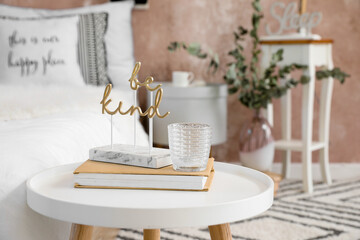Bedside table with books and decor in stylish bedroom