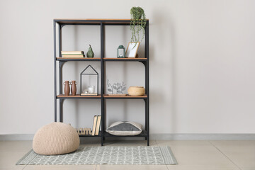 Modern shelf unit with books and decor near white wall in room