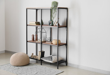 Modern shelf unit with books and decor near white wall in room