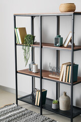 Modern shelf unit with books and decor near white wall in room