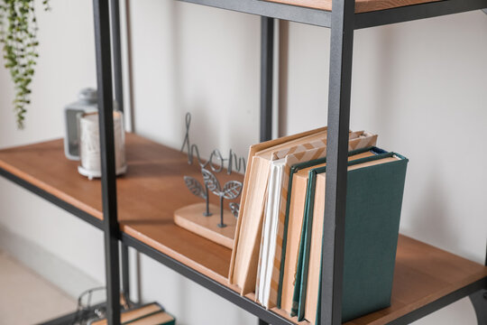 Modern shelf with books and decor near white wall, closeup