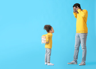 Cute African-American girl greeting her dad on Father's Day against color background