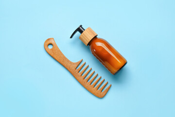 Wooden hair comb with cosmetic serum on color background
