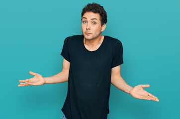 Young handsome man wearing casual black t shirt clueless and confused expression with arms and...