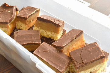 Millionaire's shortbread with chocolate and caramel in a plastic box.