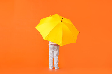 Cute little boy with umbrella on color background, back view