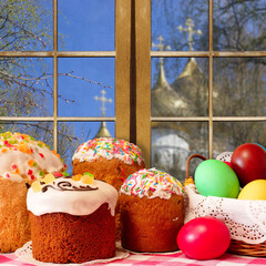 Easter. Easter cakes and colorful eggs on the background of the window. Outside the window of the dome of the temple - 429833075