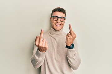 Hispanic young man wearing casual turtleneck sweater showing middle finger doing fuck you bad...