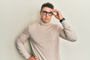 Hispanic young man wearing casual turtleneck sweater worried and stressed about a problem with hand on forehead, nervous and anxious for crisis