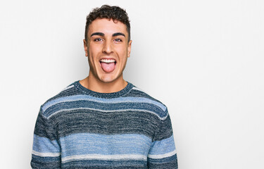 Hispanic young man wearing casual clothes sticking tongue out happy with funny expression. emotion...