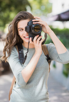 Young woman photographer takes photographs with dslr camera in a city. Travel, vacations, professional freelance work, home hobby and active lifestyle concept