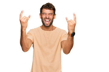 Fototapeta premium Handsome young man with beard wearing casual tshirt shouting with crazy expression doing rock symbol with hands up. music star. heavy music concept.