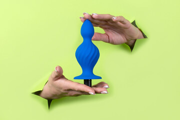 Toys for adults in women's beautiful hands on a green background. Sex shop concept