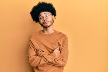 Fototapeta na wymiar Young african american man with afro hair wearing casual winter sweater smiling looking to the side and staring away thinking.