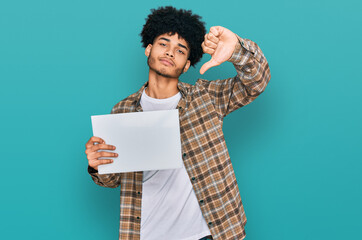Young african american man with afro hair holding blank empty banner with angry face, negative sign...