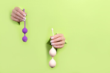 Toys for adults in women's beautiful hands on a green background. Sex shop concept