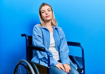 Beautiful caucasian woman sitting on wheelchair relaxed with serious expression on face. simple and...