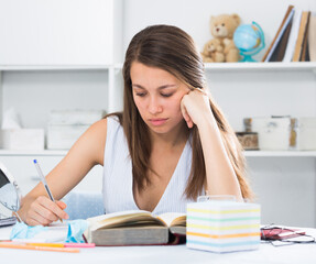 Student girl is reading text at home.