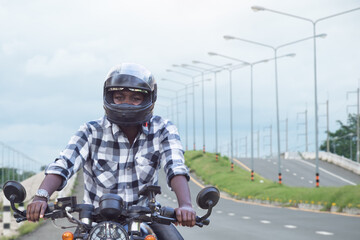 African biker in the helmet riding a motorcycle rides on highway road
