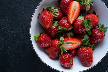 Fresh strawberries in a bowl on a dark background