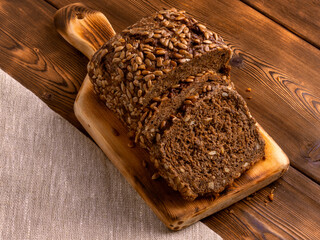 Loaf of whole grain bread on wooden background