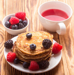 Pancakes And Berries With Red Tea On Wooden Background