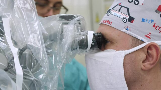 neurosurgeon looks through a microscope