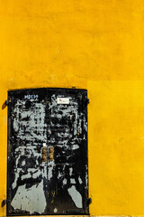 worn black double door on yellow wall