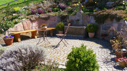 Gartenterrasse mit Tisch, Stuhl, Brunnen und Pflanzen
