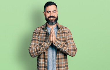 Obraz premium Hispanic man with beard wearing casual shirt praying with hands together asking for forgiveness smiling confident.