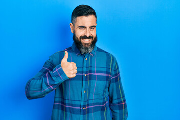 Young hispanic man wearing casual clothes doing happy thumbs up gesture with hand. approving expression looking at the camera showing success.