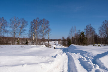 Snow-covered rural road on a frosty winter cloudless and sunny day.