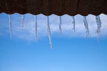 Icicles on the roof. Winter concept. against the blue sky