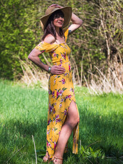 Woman with yellow dress in springtime nature, glasses and hat.