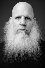 Mature bald man with long white beard in black and white