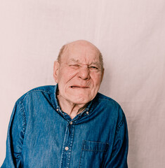 a cheerful old man with wrinkles grimaces and makes faces on a white background.