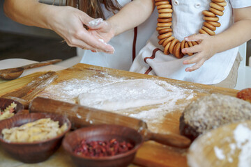 child with his mother in the kitchen sprinkles flour dough. Products from dough, flour, bakery, bread. Master Class. cook and learn