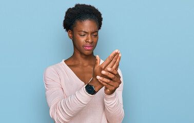 Young african american girl wearing casual clothes suffering pain on hands and fingers, arthritis...