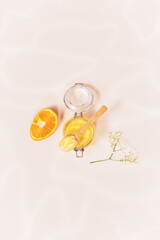 Vertical cosmetic composition with citrus scrub in a glass jar with a wooden spoon and orange on a light background with water highlights. Natural, organic beauty product in eco friendly packaging