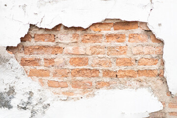 Cracked and broken white cement surface wall outside that shows the brick wall pattern inside of it