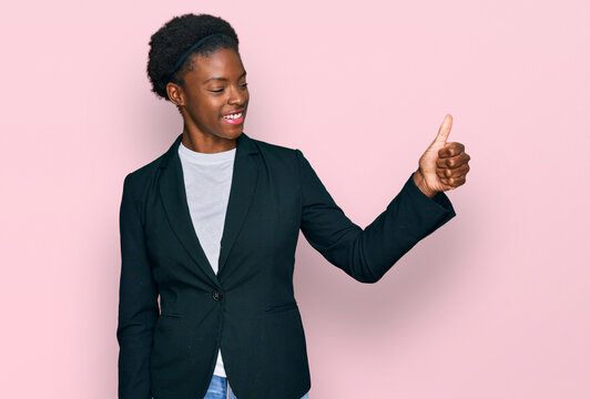 Young african american girl wearing business clothes looking proud, smiling doing thumbs up gesture to the side