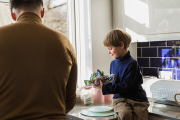 A young father washes the dishes with his son. Parenting. Communication.