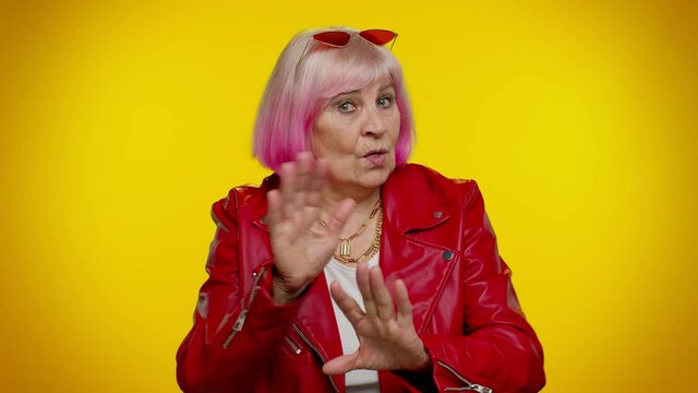 I am dont want it, not me. Confused senior granny woman rocker pointing fingers himself ask say who why me no thanks i do not need it. Yellow studio background. Elderly stylish grandmother pensioner