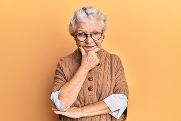 Senior grey-haired woman wearing casual clothes and glasses looking confident at the camera smiling...