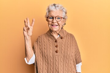 Senior grey-haired woman wearing casual clothes and glasses showing and pointing up with fingers...
