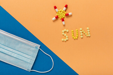 Word Sun wrote with colorful pills and protective face mask as a concept of vacation on pandemic time with prevention. Summer Time with medicine from coronavirus, vitamins are taken from the sun.